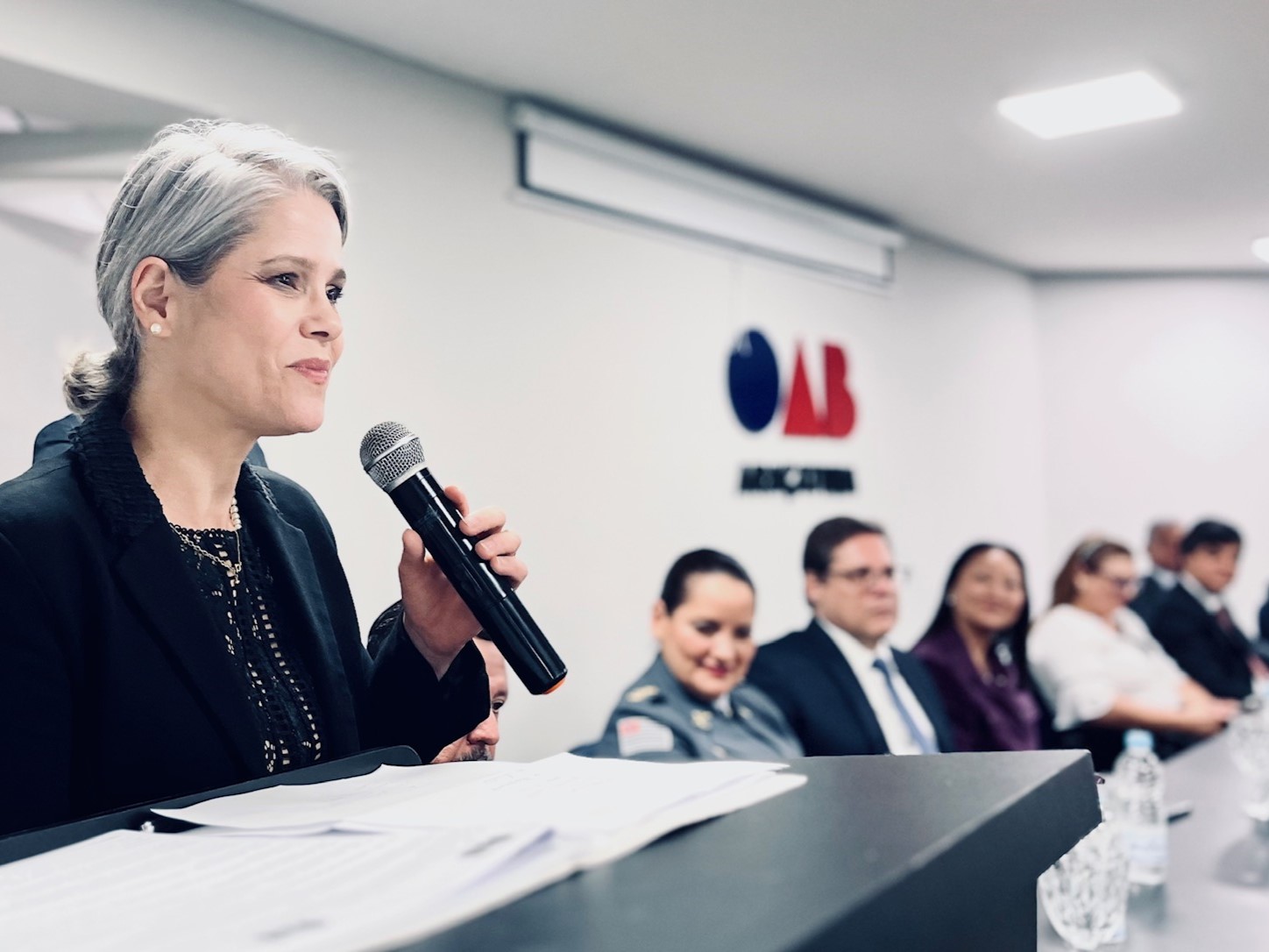 Uma mulher de terno fala em um microfone.