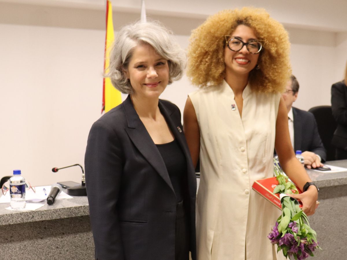 mulher grisalha à esquerda, e mulher negra, de óculos, à direita, sorrindo para a foto