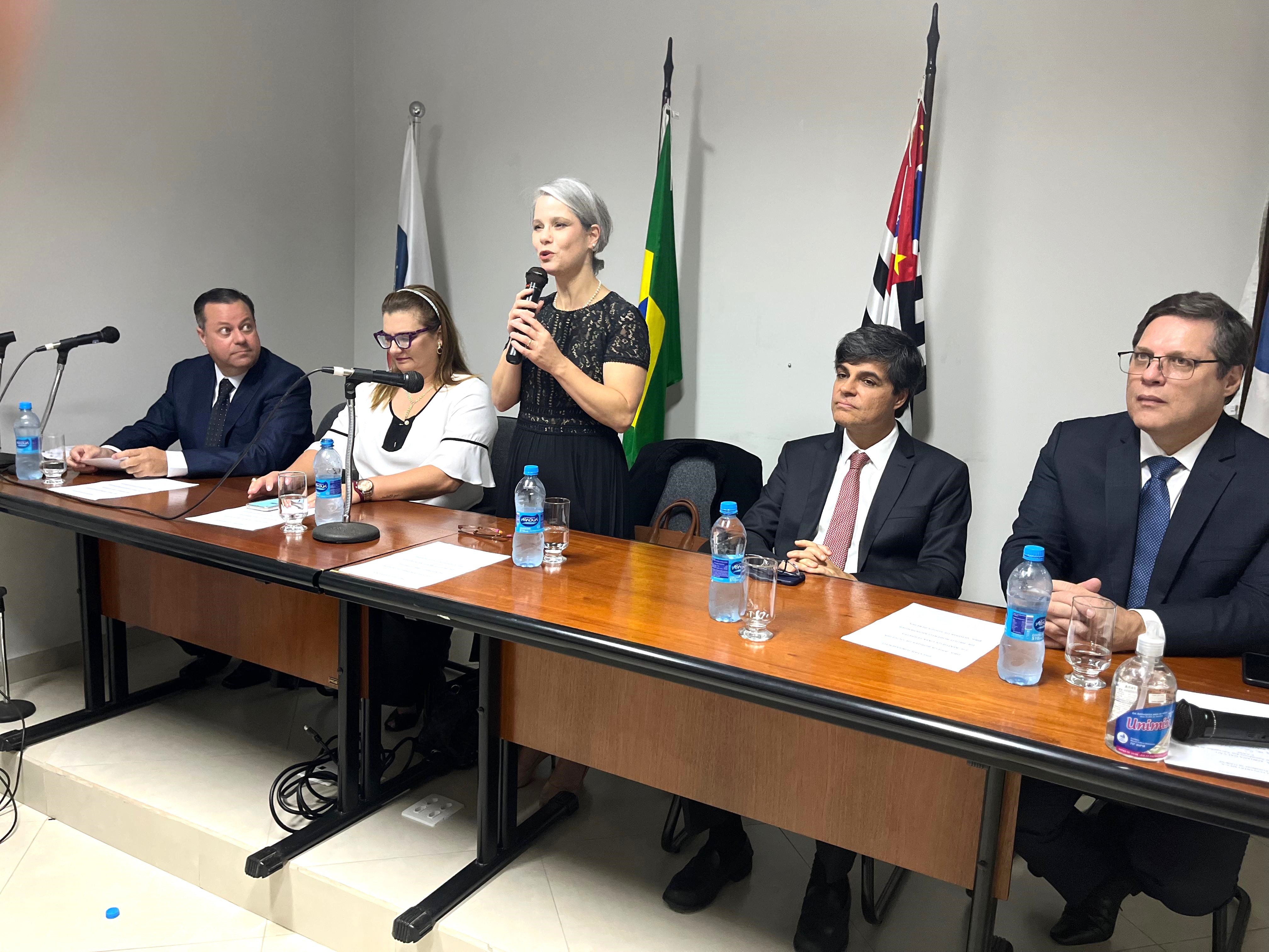 Um grupo de pessoas sentadas em uma mesa com microfones.