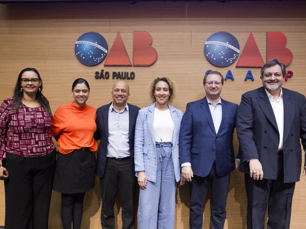 Grupo de seis pessoas a frente de painel com símbolos escritos OAB São Paulo e OAB Caasp.